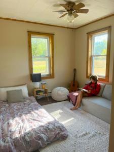 a girl sitting on a couch in a bedroom at Cozy Creek House in Forestburgh