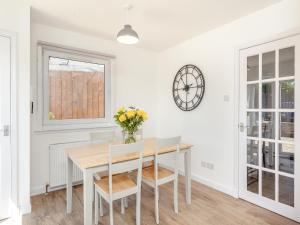 ein Esszimmer mit Tisch und Stühlen und einer Uhr in der Unterkunft Dove Cottage in Inverness