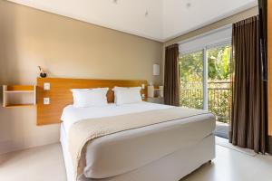 a bedroom with a large bed and a large window at Vilinha típica - Suíte Onze Tuin - Entrada com senha - Somos hospedagem por temporada in Holambra