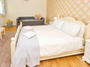 ein Schlafzimmer mit einem weißen Bett und einer Couch in der Unterkunft Arden Cottage in Twynholm + 7 Fotos