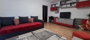 un soggiorno con divano rosso e TV di La Bloc Apartment a Arad