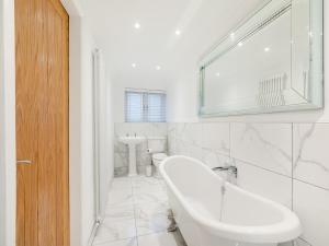 een witte badkamer met een bad en een wastafel bij Violet Cottage - Uk45968 in Yarm