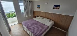 a bedroom with a bed with purple sheets and a window at Ecopousada Miriti in Belém