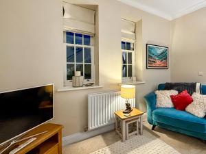a living room with a blue couch and a tv at The Court House - Uk43908 in Silloth