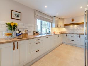 Una cocina con gabinetes blancos y un fregadero. en Llwyncelyn Farmhouse, en Clynderwen