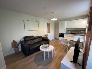 a living room with a black leather couch and a table at L'Annexe in Pontchâteau