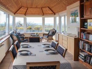 a dining room with a table and chairs and windows at Rhandir-Mwyn - Hw7110 in Llandwrog