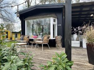 un hangar noir avec des chaises et une table sur une terrasse dans l'établissement ChaletPool, nabij het Leekstermeer, à Matsloot