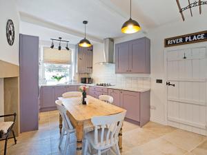 eine Küche mit einem Holztisch und weißen Schränken in der Unterkunft Duck Cottage in Gargrave