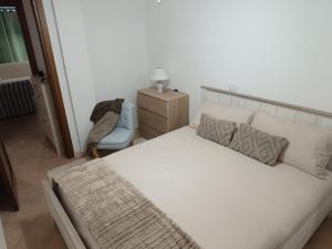 ein Schlafzimmer mit einem großen weißen Bett und einem Stuhl in der Unterkunft Casa vacanza - Ambra's Homes in Trinità dʼAgultu + 21 Fotos
