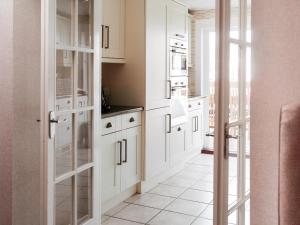 a kitchen with white cabinets and a white tile floor at Drumwherry By The Sea in Monreith