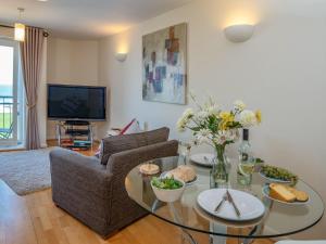 ein Wohnzimmer mit Tisch und Stühlen und einem Fernseher in der Unterkunft 8 Belvedere Court in Paignton