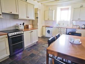 a kitchen with a wooden table and a kitchen with a stove and sink at Penrhyn Mawr - Hw7642 in Aberdaron