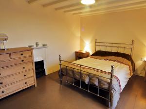 a bedroom with a bed and a dresser and a fireplace at Penrhyn Mawr - Hw7642 in Aberdaron