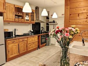 eine Küche mit Holzschränken und einer Vase aus Blumen in der Unterkunft Alpissima - Esprit chalet & confort moderne en Haute-Savoie in Taninges + 23 Fotos