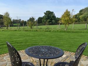a table and chairs on a patio with a field at Moorhens in Herstmonceux