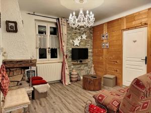 ein Wohnzimmer mit einer Steinmauer und einem Kronleuchter in der Unterkunft Alpissima - Esprit chalet & confort moderne en Haute-Savoie in Taninges