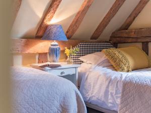 a bedroom with two beds and a table with a lamp at Woolhouse Barn in Hunton