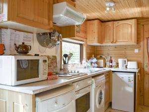 a kitchen with a microwave and a washer and dryer at Fell View Lodge in Keswick