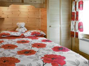a teddy bear sitting on top of a bed at Fell View Lodge in Keswick