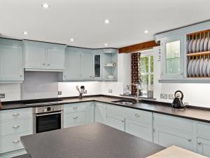 eine Küche mit weißen Schränken und schwarzen Arbeitsplatten in der Unterkunft Temple Barn in Abercastle + 12 Fotos