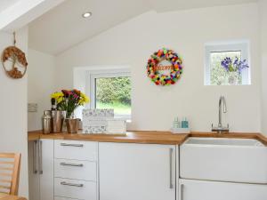 eine Küche mit weißen Schränken und einer Spüle und einem Fenster in der Unterkunft Manor Park Cottage in Knitsley + 16 Fotos