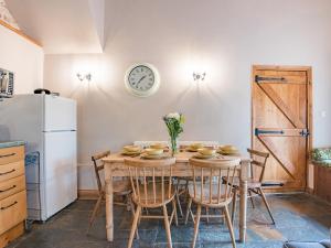 a kitchen with a table with chairs and a refrigerator at Kingfisher Oast in Hollingbourne