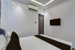 ein weißes Schlafzimmer mit einem Bett und einem Fernseher in der Unterkunft Hotel O Royal Fourtune in Utrān