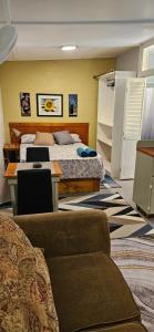 a bedroom with two beds and a desk and a couch at Gloria's mini hideaway in Christ Church