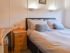 a bed with white sheets and pillows next to a night stand at Tranquillity in Millom +16 photos