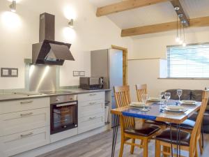 a kitchen with a table with chairs and a stove at Llety'r Saer in Pen-y-bont-fawr