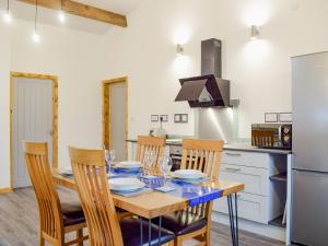 a kitchen with a table with chairs and a refrigerator at Llety'r Saer in Pen-y-bont-fawr