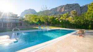 ein Swimmingpool mit Stühlen und Bergen im Hintergrund in der Unterkunft Welt Bungalows Belenbaşı in Hurmaköy