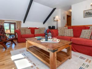 ein Wohnzimmer mit roten Sofas und einem Holztisch in der Unterkunft Carn Llidi Cottage in St. Davids