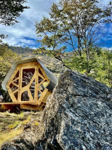 a small wooden house with a large rock at Surí refugios Aquasol, Carretera Austral, Cochrane in Cochrane