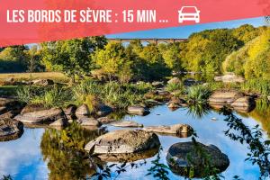 a bridge over a river with rocks in the water at Studio aux portes du Puy duFou in Les Herbiers