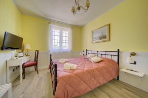 Un dormitorio con cama, escritorio y televisión. en Il Roseto dei Sensi, en Tarantasca