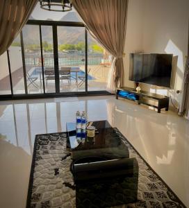 a living room with a television and a table at Al Dana Palma Villa - Luxury 4-bedroom villa with Heated Pool & Mountain Sea View in Fujairah +21 photos