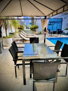 a table and chairs with an umbrella and a pool at Al Dana Palma Villa - Luxury 4-bedroom villa with Heated Pool & Mountain Sea View in Fujairah