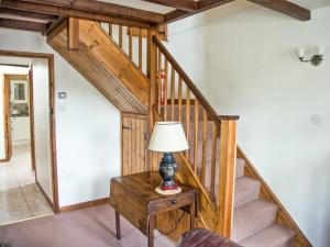 Una habitación con una escalera con una lámpara sobre una mesa. en East Granary - 28956, en Eye