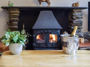 a fireplace with a bottle of champagne on a table at Ty Lewis Cottage in Llanelli