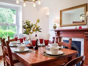 a dining room with a wooden table with red wine glasses at Ty Lewis Cottage in Llanelli