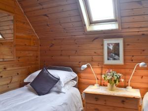 a bedroom with wooden walls and two beds and two lights at Wee Ben in Bridge of Tilt +3 photos
