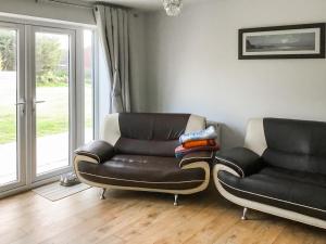 a living room with two chairs and a leather couch at Hempstead End in Lessingham