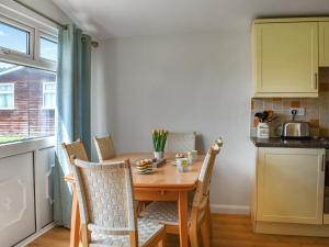 eine kleine Küche mit einem Holztisch und Stühlen in der Unterkunft Boobys Bay - Uk47554 in Saint Merryn