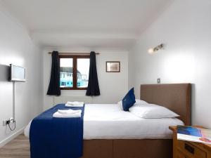 a bedroom with a bed with blue and white sheets and a window at Heron in Wroxham +3 photos