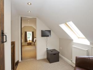 Zimmer im Dachgeschoss mit einem Dachfenster und einem TV an der Wand in der Unterkunft Stable Cottage - Hw7452 in Whitford