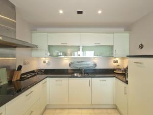 een keuken met witte kasten en zwarte aanrechtbladen bij Sea Side in Westward Ho +9 foto's