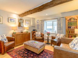 a living room with leather furniture and a large window at The Smithy - E5445 in Brassington