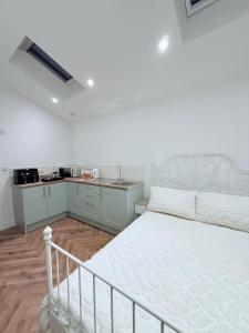a bedroom with a white bed and a kitchen at Cosy Corner Cheadle in Cheadle